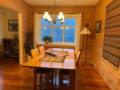 a dining room with a table with chairs and a window at Jåstad Gjestetun in Jåstad