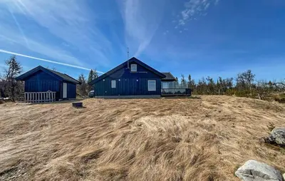 a blue house sitting on top of a field at Cozy Home In Ulnes With Sauna in Ulnes