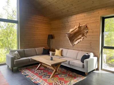 a living room with a couch and a wooden wall at The Lookout At Beitostølen in Beitostøl