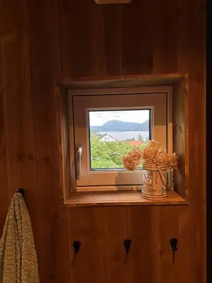 a window in a room with a vase of flowers at Architectural gem with fjord view in Holmedal