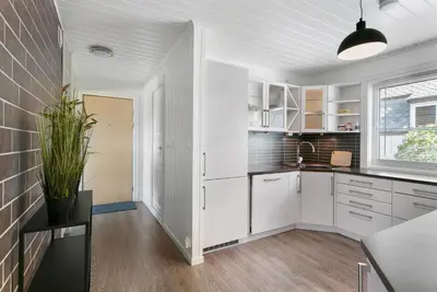 a kitchen with white cabinets and a brick wall at Centrum Apartment in Ålesund