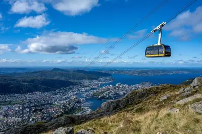 a gondola flying over a city on a mountain at Historic Apartment in the Heart of Bergen in Bergen