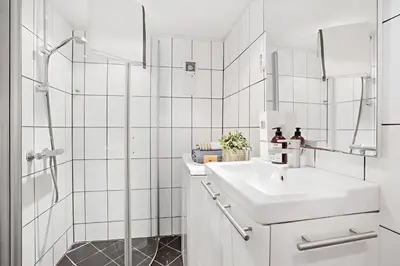 a white bathroom with a sink and a shower at Historic Apartment in the Heart of Bergen in Bergen