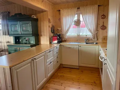 a kitchen with white cabinets and a sink and a window at Koselig Og Sentral Hytte Med Peis Og Badstue in Beitostøl