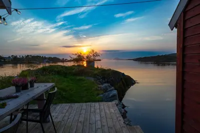 a sunset over a body of water with a table at Vár Seaside Cabin in Stavang