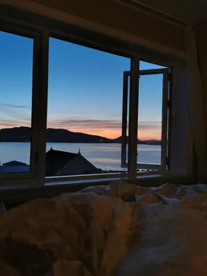 a bedroom with a view of the ocean from a window at Cozy house in historical area in Bergen