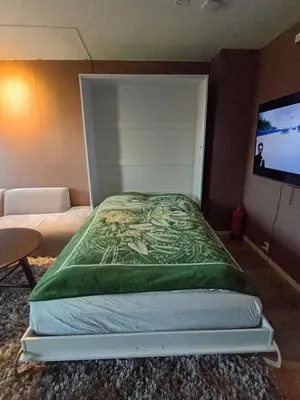 a bed in a room with a flat screen tv at Cozy Studio in Hallset, Trondheim in Trondheim