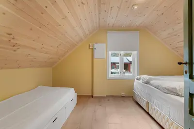 two beds in a room with a wooden ceiling at Jordeplegarden Apartments in Tønjum