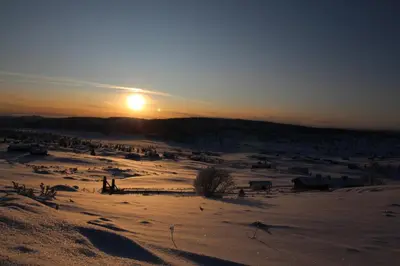 a snowy field with the sun setting in the background at Mountain Lodge - Midtgardstunet in Ringebu