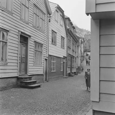 a woman standing on a street next to buildings at The 1880 Authentic Bergen Dream I 500m to Bryggen in Bergen