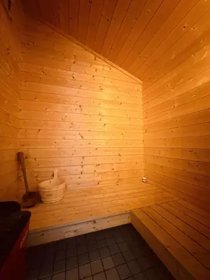 a sauna with a wooden wall and a bucket at Familiehytte med fantastisk beliggenhet i Vestlia in Geilo