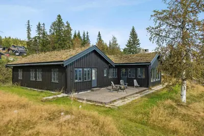 a black cabin with a deck in the grass at Bo På Norefjell Rett Ved Alpint Og Langrenn in Noresund