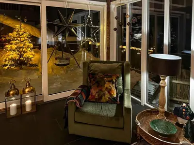 a living room with a chair and a christmas tree at Panoramic Apartment In The Heart Of Beitostølen in Beitostøl