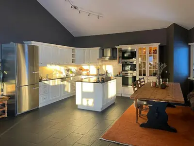a large kitchen with white cabinets and a wooden table at Panoramic Apartment In The Heart Of Beitostølen in Beitostøl
