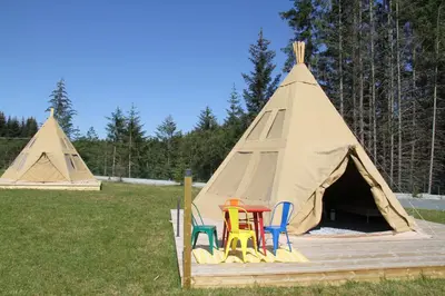 a teepee with chairs and toys in it at Alpakkaparken Glamping med parktilgang