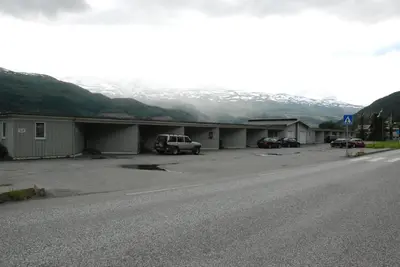 a parking lot with cars parked next to a mountain at Fleischer's Motel in Vossevangen