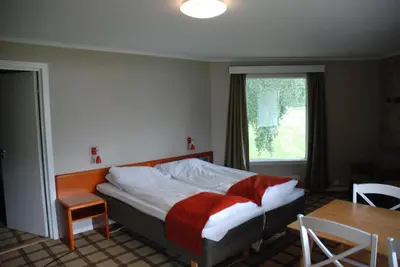 a bedroom with a bed and a table and a window at Fleischer's Motel in Vossevangen