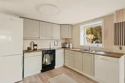 a kitchen with white cabinets and a sink and a window at Aurora Bliss - Waterfront Jacuzzi & Sauna near Bergen in Askøy