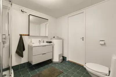 a white bathroom with a sink and a toilet at Aurora Bliss - Waterfront Jacuzzi & Sauna near Bergen in Askøy