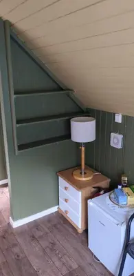 a lamp on a dresser in a room with green walls at Cozy bedroom & basement with amenities in Odda