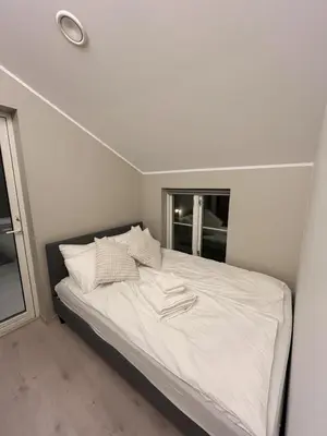 a bed with white sheets and pillows in a bedroom at Trondheim's smallest detached house in the middle of the city centre! in Trondheim