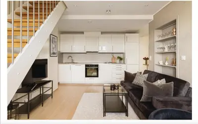 a living room with a couch and a kitchen at Bergenhus apartment in historical Sandviken in Bergen