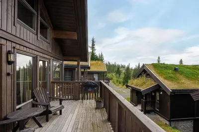 a deck with a bench and a grill on a house at Large family cabin at Hafjell with ski in-ski out in Hafjell