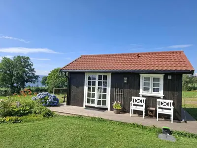a small black shed with two chairs and flowers at Lovely tiny house with a dream view !