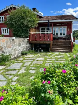a house with a deck and a yard with flowers at Family Cabin By Lake Mylla With Private Dock in Lunner