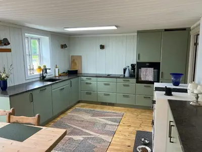 a large kitchen with green cabinets and a table at Family Cabin By Lake Mylla With Private Dock in Lunner