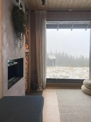 a living room with a fireplace and a large window at Mountain Cabinin Valdres in Aurdal