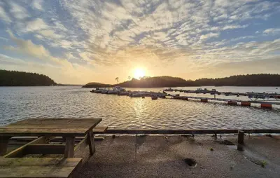 a dock with boats in the water with the sunset at Beautiful Home In Bøvågen With Sauna in Bøvågen