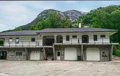 a house with three garage doors and a mountain at 3 Bedroom Lovely Apartment In Eidfjord in Eidfjord