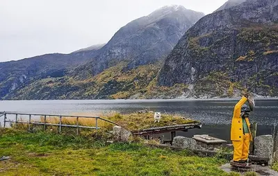 a person standing next to a body of water at 3 Bedroom Lovely Apartment In Eidfjord in Eidfjord