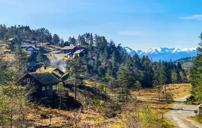 a house on a hill with mountains in the background at 3 Bedroom Awesome Home In Strandebarm in Strandebarm