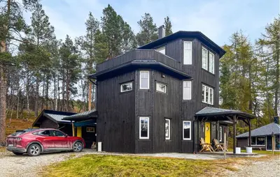 a black house with a red car parked in front of it at Stunning Home In Røros With Sauna in Røros