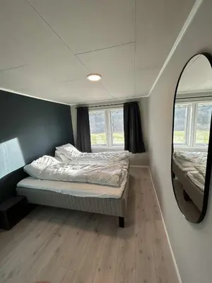 a small bedroom with a bed and a mirror at Villa Isfjorden in Isfjorden