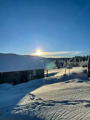 a building in the snow with the sun behind it at Family-Friendly Seter Cabin Near Makalaus Peak in Reinli