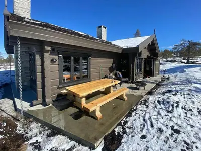 a log cabin with a picnic table in the snow at Large Dream Cabin On Vegglifjell in Veggli