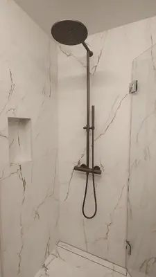 a shower in a bathroom with white marble at Splitter ny leilighet i sokkel på enebolig in Vikhammer