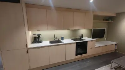 a kitchen with white cabinets and a sink and a stove at Splitter ny leilighet i sokkel på enebolig in Vikhammer