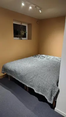 a bedroom with a bed with a black and white blanket at Splitter ny leilighet i sokkel på enebolig in Vikhammer