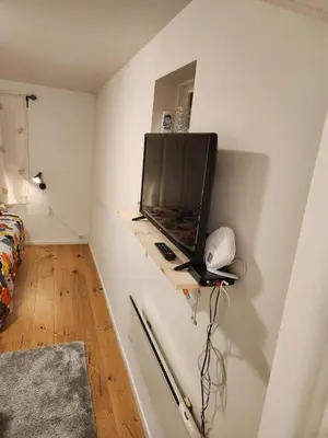 a room with a tv on a shelf in a wall at Nice Apartment in Sjetnemarka - Free parking and WiFi in Trondheim