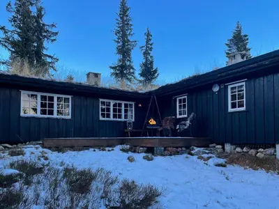 a black house with a fire in front of it at Family Cabin From 1968 At Norefjell in Noresund
