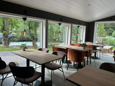 a restaurant with wooden tables and chairs and windows at Nygård Panorama in Stryn