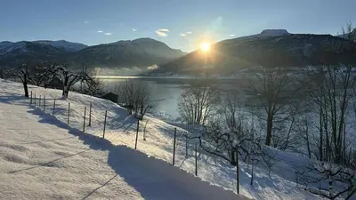 a fence in the snow next to a body of water at Casa Hauge - Fjord View in Sandane