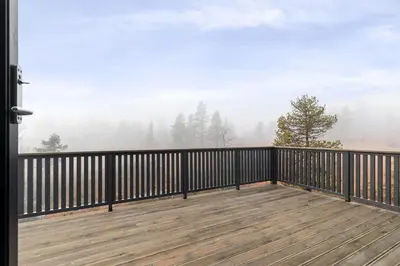 a balcony with a view of a foggy forest at NEW cozy and large lodge with private Jacuzzi and sauna in Eggedal