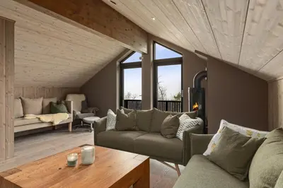 a living room with a couch and a table at NEW cozy and large lodge with private Jacuzzi and sauna in Eggedal