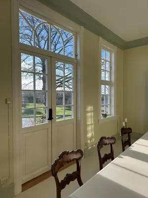 a dining room with a table and chairs and windows at Historic villa with large garden in Stord