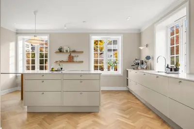 a large kitchen with white cabinets and windows at Unik villaeiendom, totalrenovert i klassisk stil in Trondheim